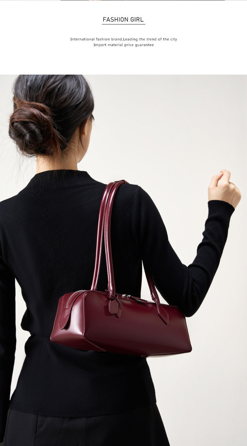 Fashionable woman carrying a winter leather baguette bag in burgundy, showcasing elegance and style.