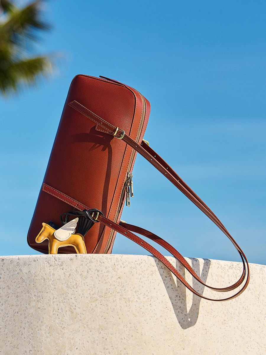 leather bowling handbag from the Dreamland Series with a decorative charm in a sunny outdoor setting.
