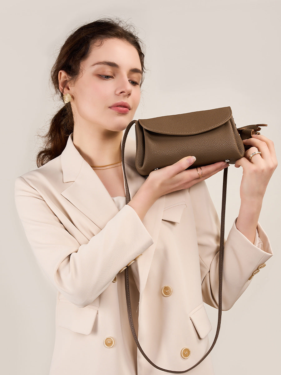 Woman in a beige blazer holding a Mini Soft Cowhide Leather Bag in brown, showcasing its compact and elegant design.