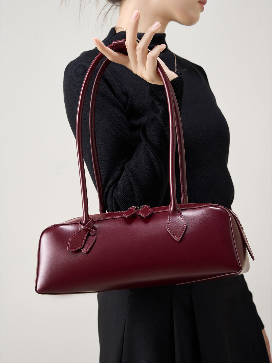 A model holding the 2025 Winter Leather Baguette Bag in burgundy, showcasing its elegant design and structured silhouette.