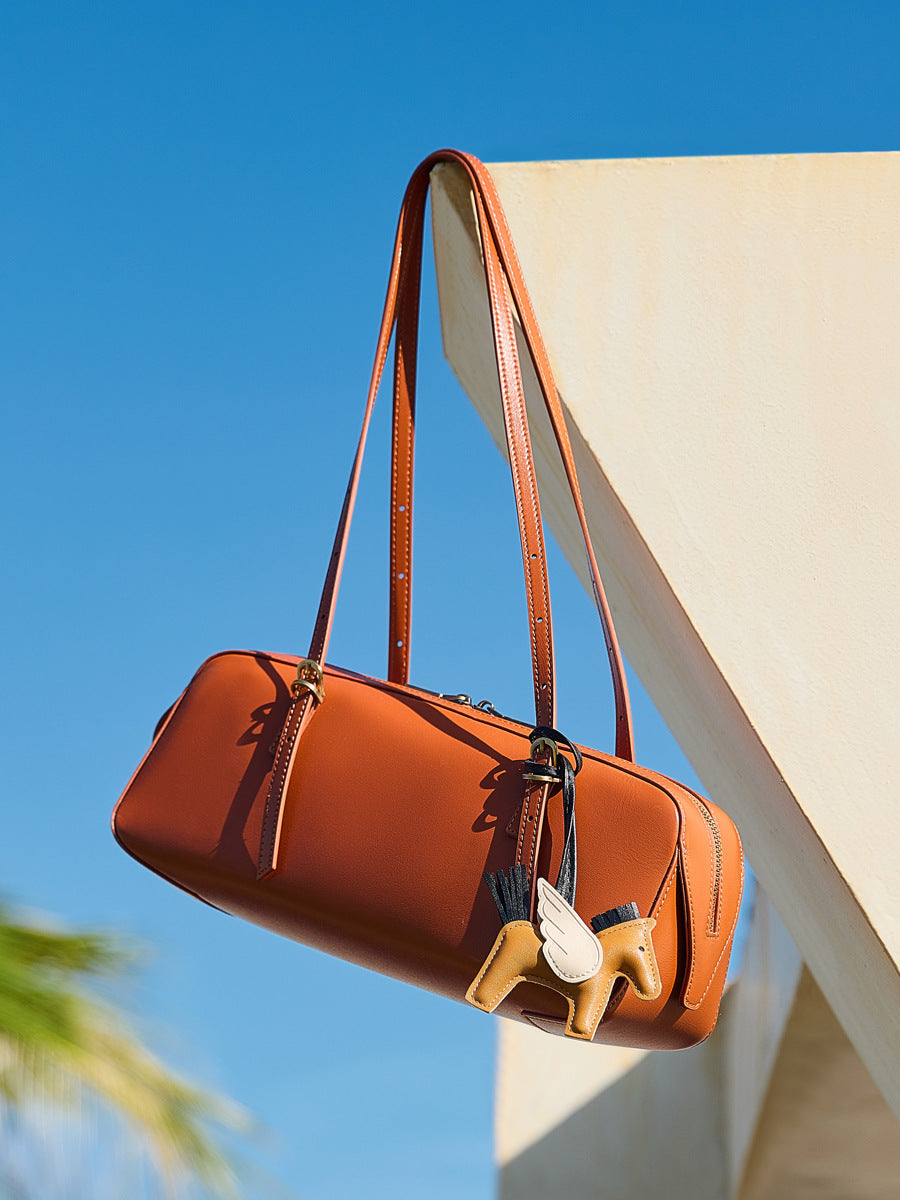 leather bowling handbag from the Dreamland Series with a decorative charm against a blue sky.