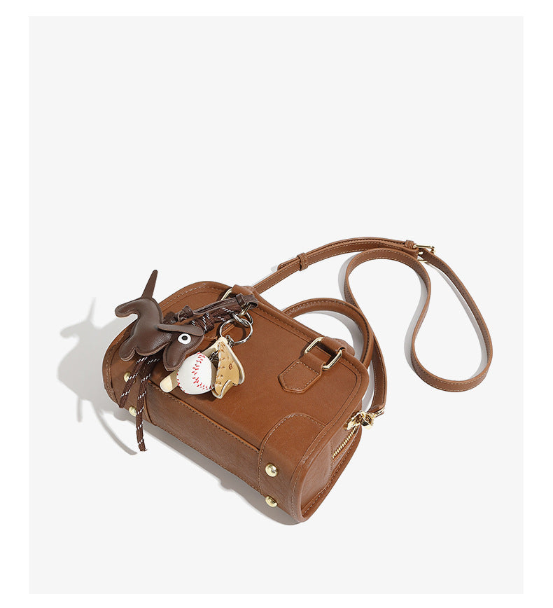 classic leather Boston bag featuring a sleek design and playful keychain accessories.