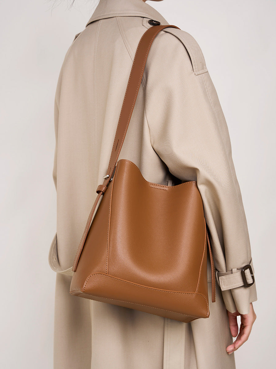 Genuine leather bucket bag in brown, showcased on a model wearing a stylish beige trench coat.