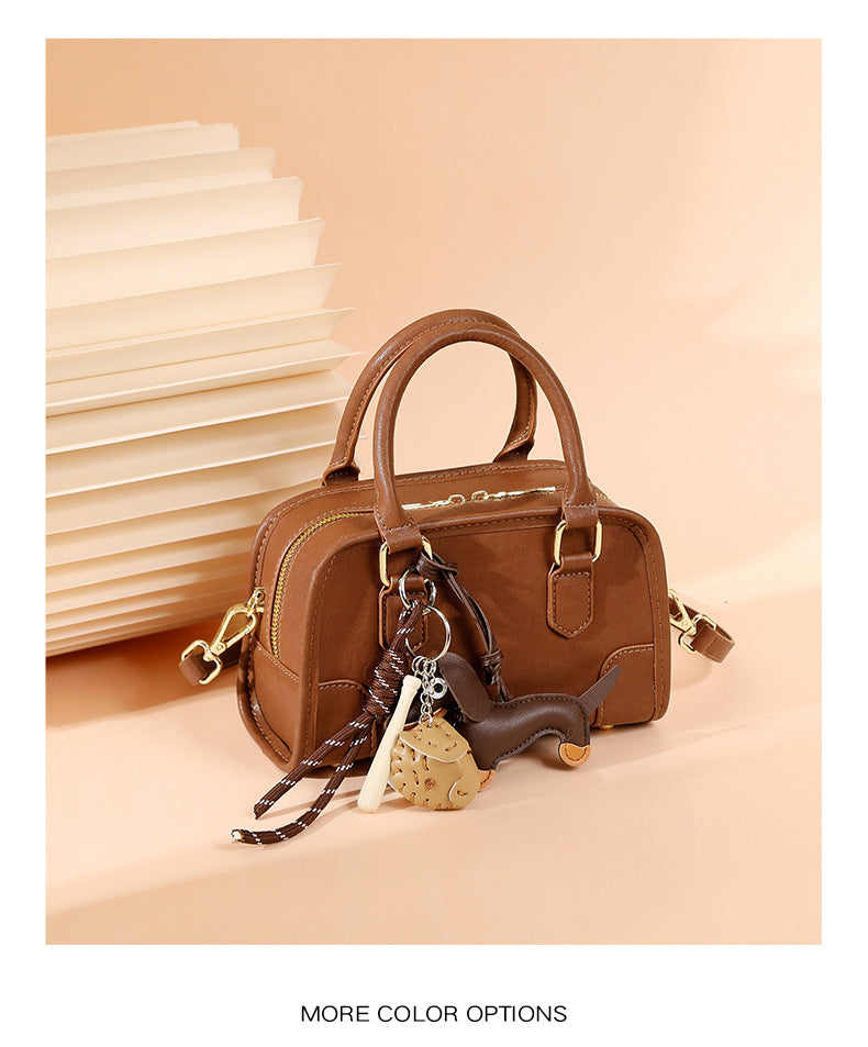classic leather Boston bag in brown with unique charm accessories and compact design.