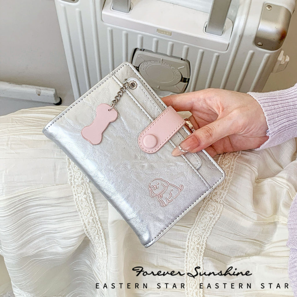 Puppy passport holder and wallet in silver with pink accents, featuring a cute puppy design and bone keychain.