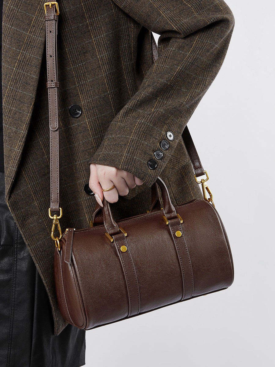 Leather vintage boston bag being held by a person in a stylish outfit.